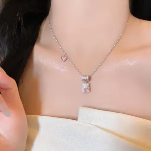 Close-up of an elegant silver-tone necklace with a zircon bear and pink hearts on a model.