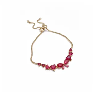 Gold adjustable bracelet featuring red heart, teardrop, and bow-shaped zircons.
