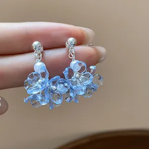 Detailed macro view of blue translucent resin flower earrings accented with white pearls