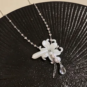 Elegant lily flower necklace with pearls and heart-shaped chain on a black display