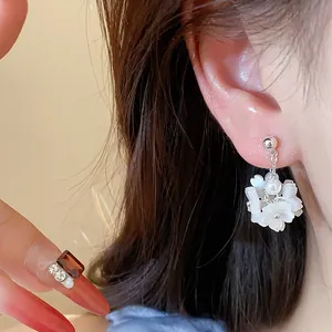 Macro detail of elegant white flower pearl stud earrings on a silver needle base