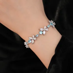 Elegant silver flower bracelet with blue and clear zirconia stones worn on a wrist.