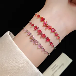 Close-up of elegant zircon heart and bow charm bracelets in red and pink on a wrist