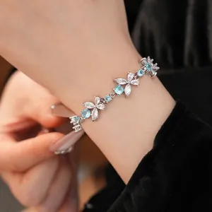 Elegant silver floral bracelet inlaid with blue and clear zircon stones worn on wrist