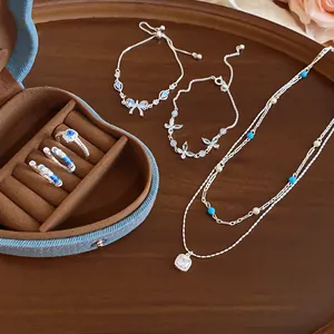 Close-up view of an elegant silver jewelry set with blue beads and pearls on wooden tray.