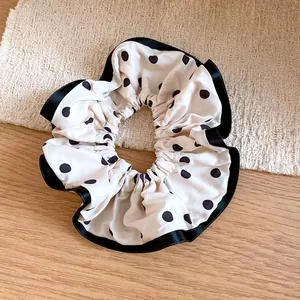 Detailed view of an elegant oversized polka dot scrunchie with black satin ribbon edges.