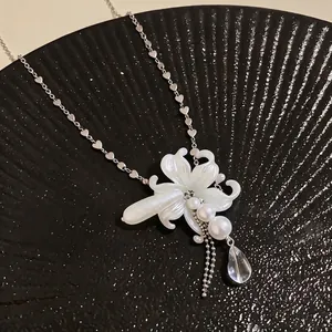 Detailed view of white lily flower necklace with pearls and clear teardrop charm