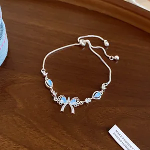 Close-up detail of a silver adjustable slider bracelet featuring a blue zircon bow charm