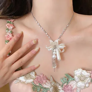Detailed view of a French style pearl flower and teardrop pendant necklace on a model