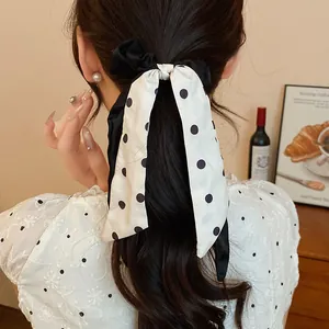 Detailed view of an elegant black and white polka dot hair scrunchie on a ponytail