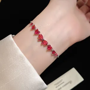 Close-up of elegant zircon bow and heart-shaped red gemstone bracelet on wrist