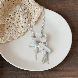 Close-up of elegant flower pendant necklace with pearls and delicate heart-shaped chain.