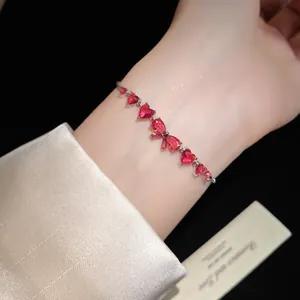 Close-up detail of silver bracelet with red heart and waterdrop zircon stones on wrist