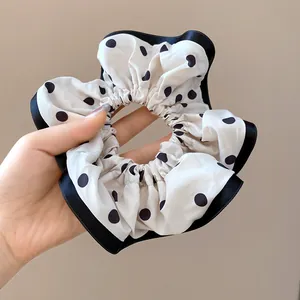 Close-up of a French style large scrunchie with classic black polka dots and ribbon edge