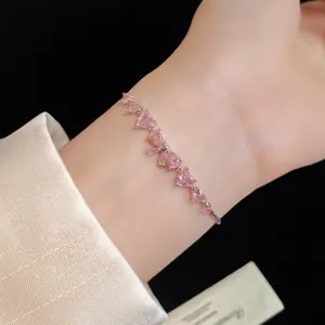 Close-up of elegant pink zircon bow and heart bracelet worn on a woman's wrist