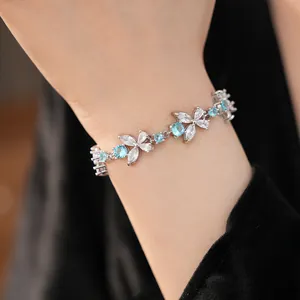 Elegant silver floral bracelet featuring sparkling blue and white zircon stones on model wrist
