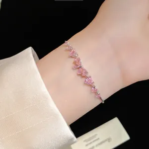 Detailed close-up of a pink zircon bow heart bracelet worn on wrist with satin