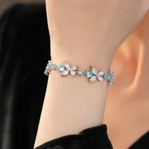Detailed close-up view of a sparkling blue zirconia flower bracelet worn on a woman's wrist