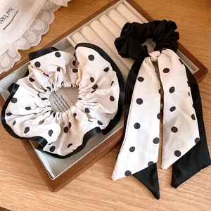 Close-up of elegant cream and black polka dot hair scrunchies with a stylish ribbon tail