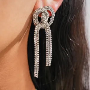 Dettaglio di orecchini a nodo in strass argento con nappine scintillanti sulla modella