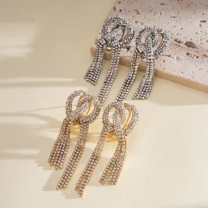 Dettaglio ravvicinato di orecchini con nappine in strass annodati nelle finiture oro e argento