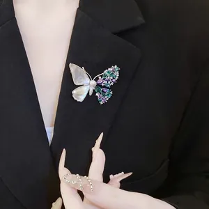 Elegant asymmetric butterfly brooch with white shell and colored zircons on a blazer