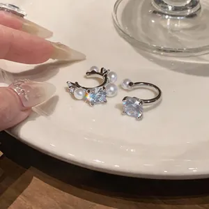 Close-up detail of elegant silver ear cuffs featuring sparkling zircons and pearls