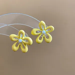 Dettaglio macro di orecchini a lobo a forma di fiore giallo con centro in smalto