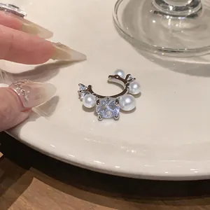 Close-up detail of a minimalist French-style zircon and pearl ear cuff for non-pierced ears