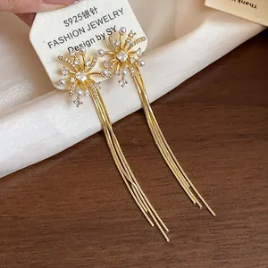 Detailed close-up of firework tassel earrings with pearls and gold plating