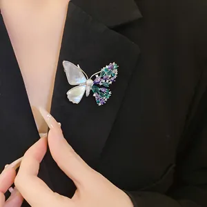 Close-up of elegant butterfly brooch with zircons and shell on black blazer lapel.