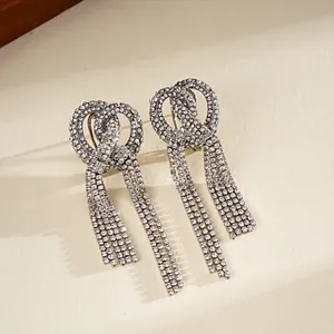 Primo piano di eleganti orecchini a nodo con lunghe nappe di strass brillanti in argento