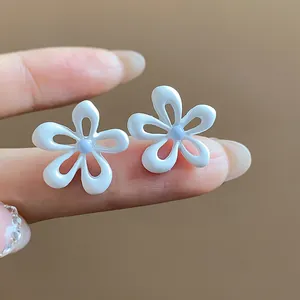 Dettaglio di orecchini a lobo a forma di fiore in smalto bianco con petali traforati