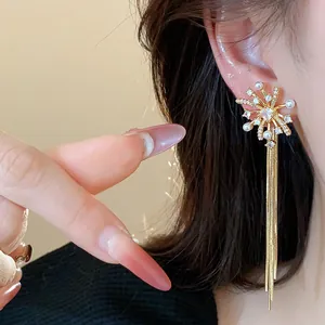Close-up of elegant firework tassel earrings with pearls in 18k gold plated finish