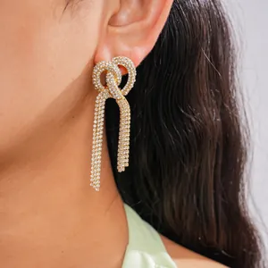 Primo piano di eleganti orecchini con strass scintillanti a forma di nodo e nappe