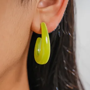 Detailed close-up showing a vibrant neon green geometric resin C-shaped hoop earring on ear