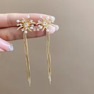Detailed close-up view of firework stud earrings with pearls and long golden tassels