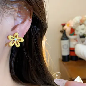 Primo piano di una modella che indossa orecchini a fiore smaltati gialli in dolce stile coreano.