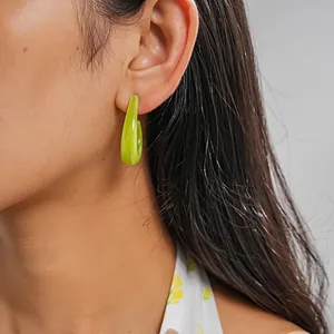 Close-up detail of a marbled green C-shaped resin hoop earring worn on a model's ear