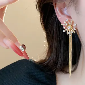 Close-up of 18k gold-plated firework earrings with pearls and long tassels on model