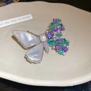 Detailed view of asymmetric butterfly brooch with pearl, shell wings and zircon gemstones