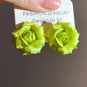 Dettaglio di orecchini a lobo a fiore verde lime con petali testurizzati su cartoncino