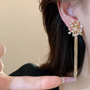 Detailed view of gold firework stud earrings with elegant pearl accents and long chain tassels
