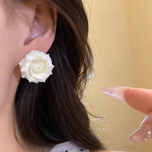 Dettaglio di un delicato orecchino a lobo a fiore di rosa bianca placcato oro 18K