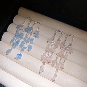 Dettaglio di orecchini a nappa con scaglie di pietra blu e rosa e brillanti strass lucidi