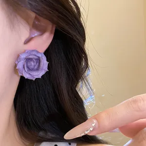 Primo piano dettagliato di un orecchino a rosa viola placcato in oro 18 carati su modella
