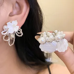 Close-up detail of white gardenia and shell-shaped beaded earrings for women