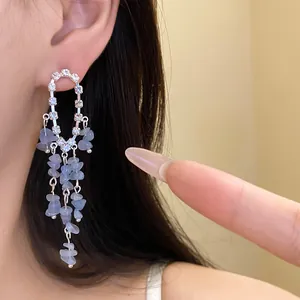 Dettaglio di orecchini in argento con nappe in pietra blu e accenti di strass lucidi