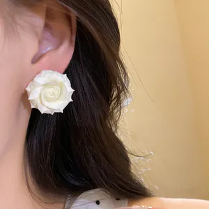 Primo piano di orecchini a perno a rosa bianca placcati in oro 18K su orecchio
