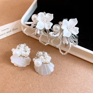 Detailed view of handmade white gardenia flower earrings with pearls and beads